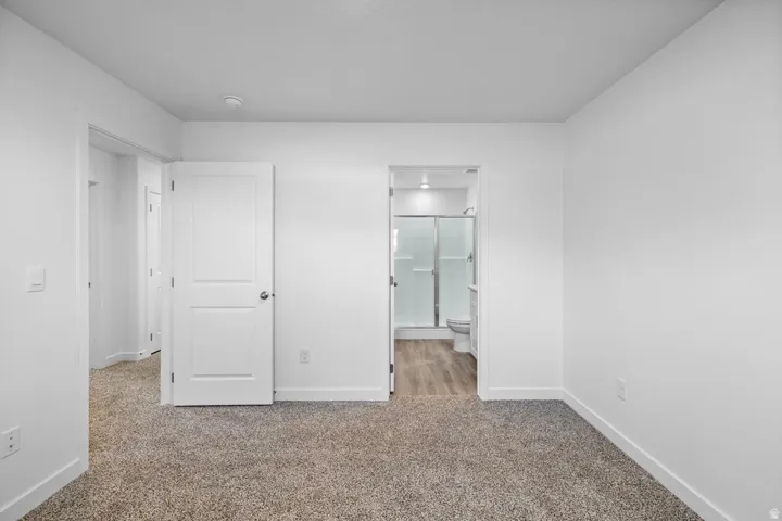 Spacious room with new carpet flooring, white walls, and bright overhead lighting