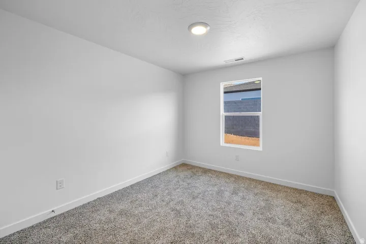 Bright room featuring plush gray carpeting, white walls, a single window, recessed lighting, and white baseboards
