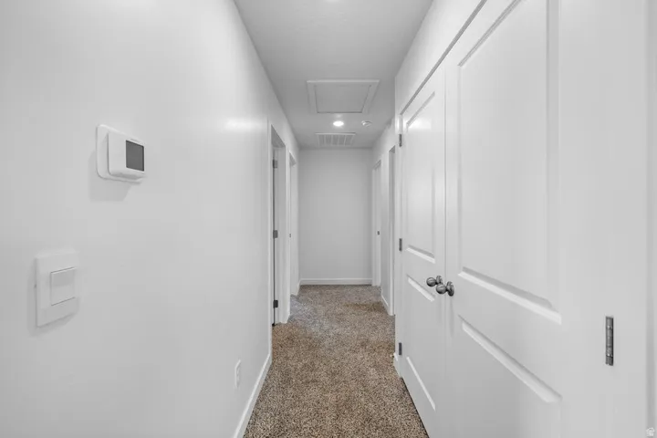Hallway featuring carpet flooring, white walls, recessed lighting, and white paneled doors with dark hardware