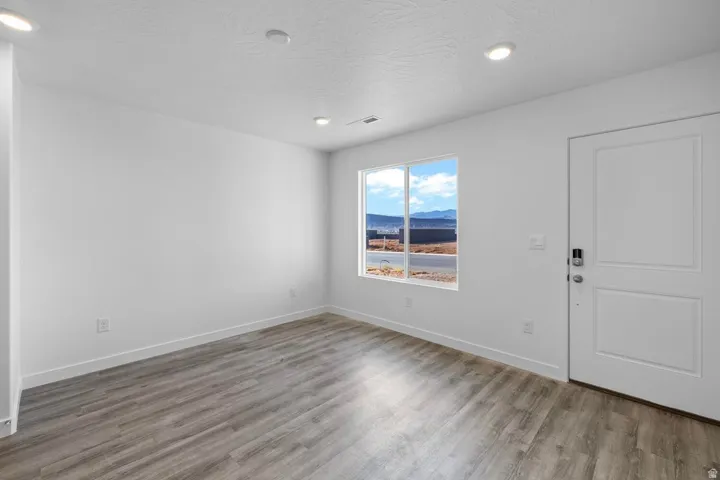Light-filled interior space featuring wood-finish flooring, recessed lighting, and a white paneled entry door with smart lock hardware