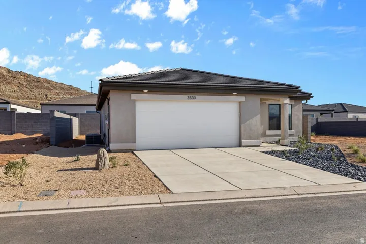 Contemporary stucco exterior featuring a dark tile roof, an integrated two-car garage, and a concrete driveway
