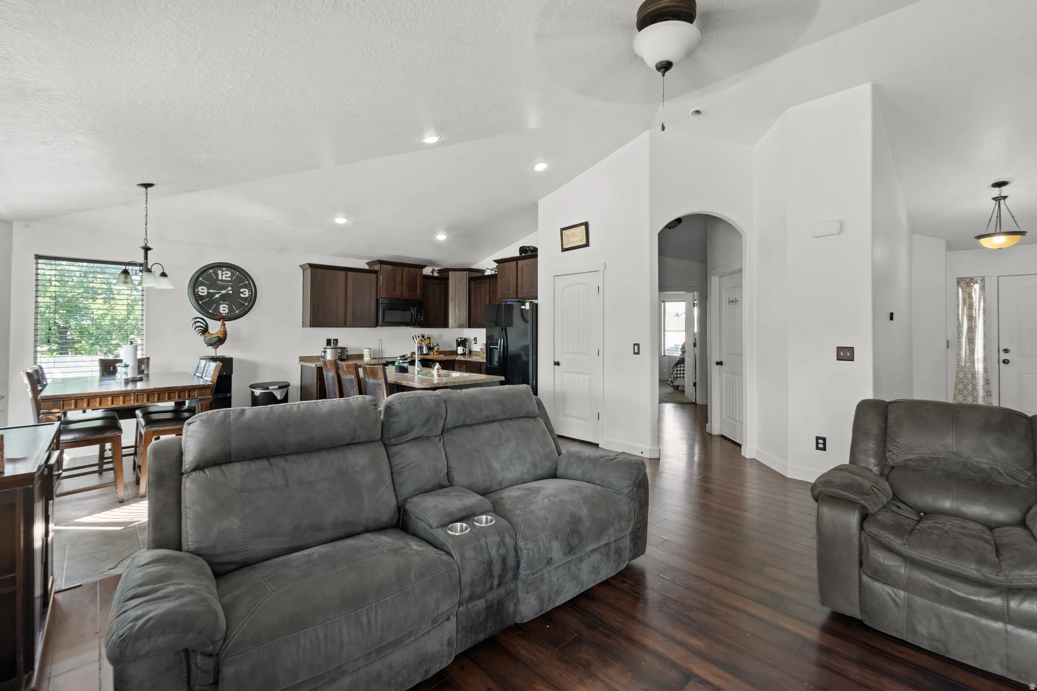Open-concept living area featuring wood-finish flooring, vaulted ceilings, and recessed lighting