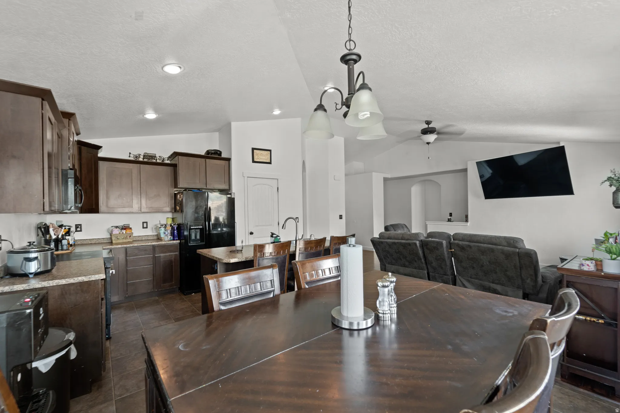 Open-concept kitchen and dining area with wood-finish cabinetry and stone-look countertops