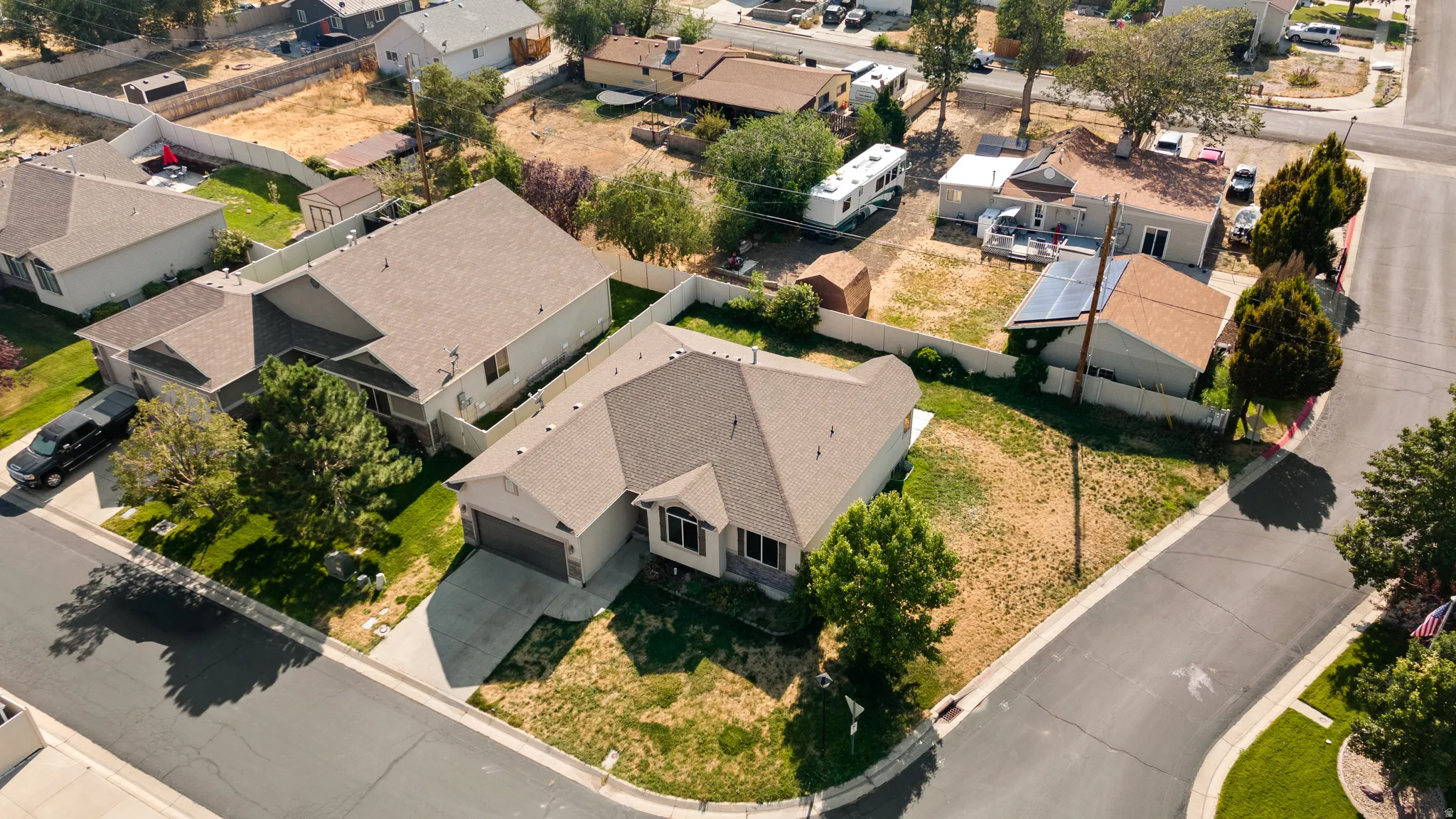 Corner lot residence featuring an attached garage, mature landscaping, and a paved driveway