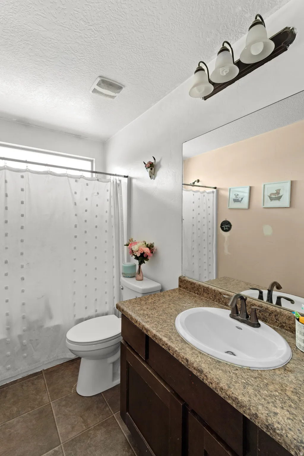 Bathroom featuring a vanity with a laminate countertop, an undermount sink, and a dark wood-finish cabinet