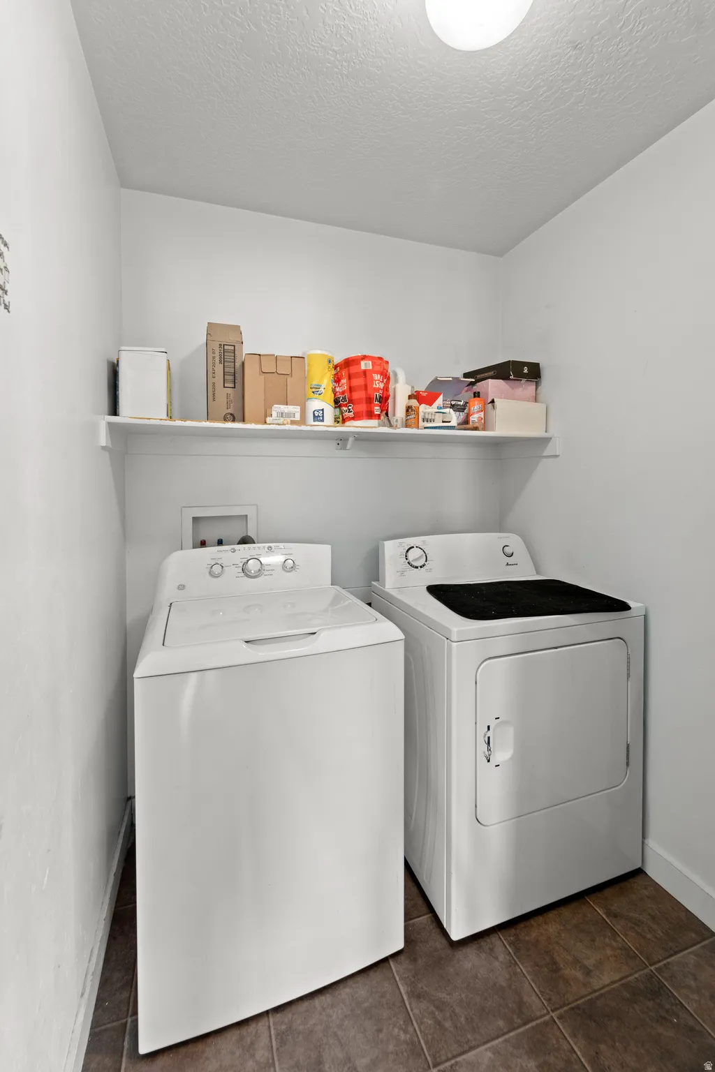 Dedicated laundry area featuring a built-in shelf, overhead lighting, and tiled flooring