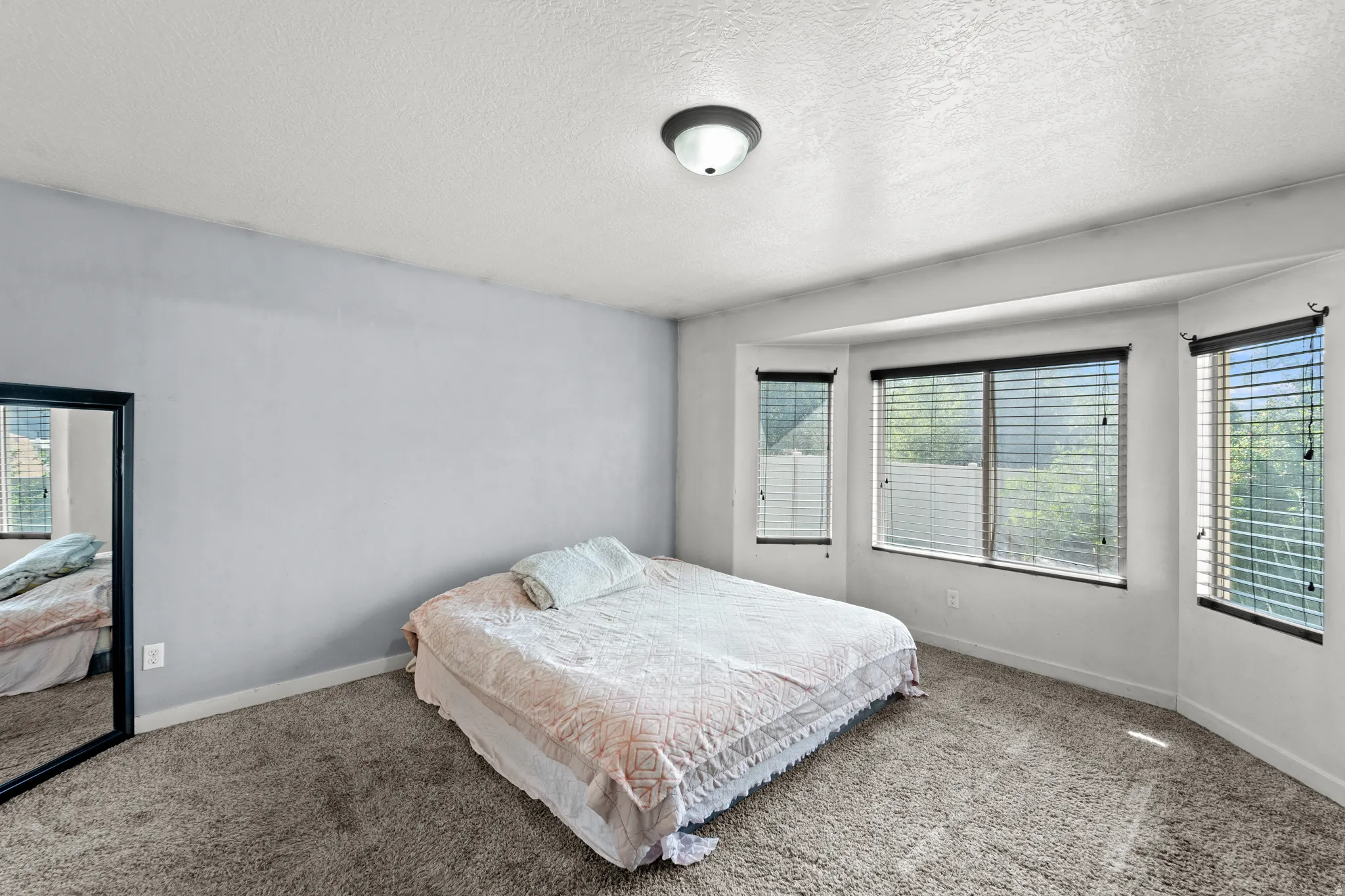 Bedroom featuring a bay window, neutral carpeting, light gray wall paint, and a semi-flush mount ceiling light
