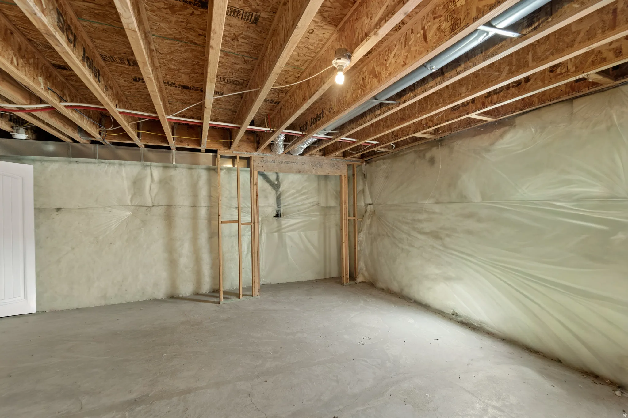 Unfinished basement space featuring exposed wood joists and subfloor ceiling