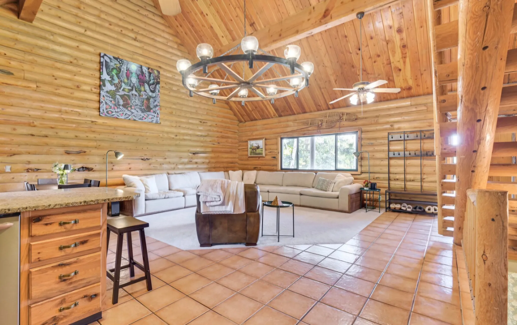 Vaulted wood-finish ceiling with exposed beams, log walls, and a grand chandelier