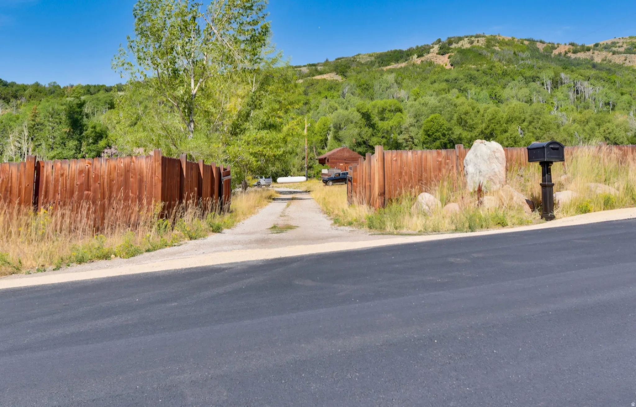 Gravel driveway framed by natural wood fencing and natural landscaping