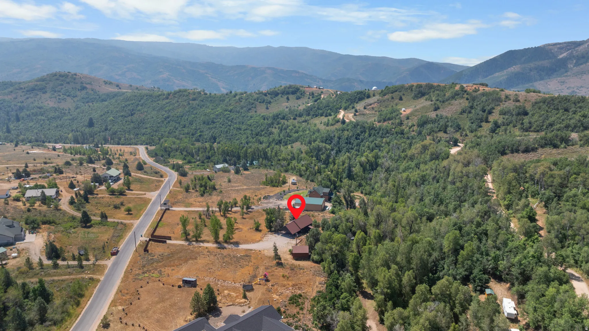 Expansive mountain landscape with a residential property nestled among mature trees