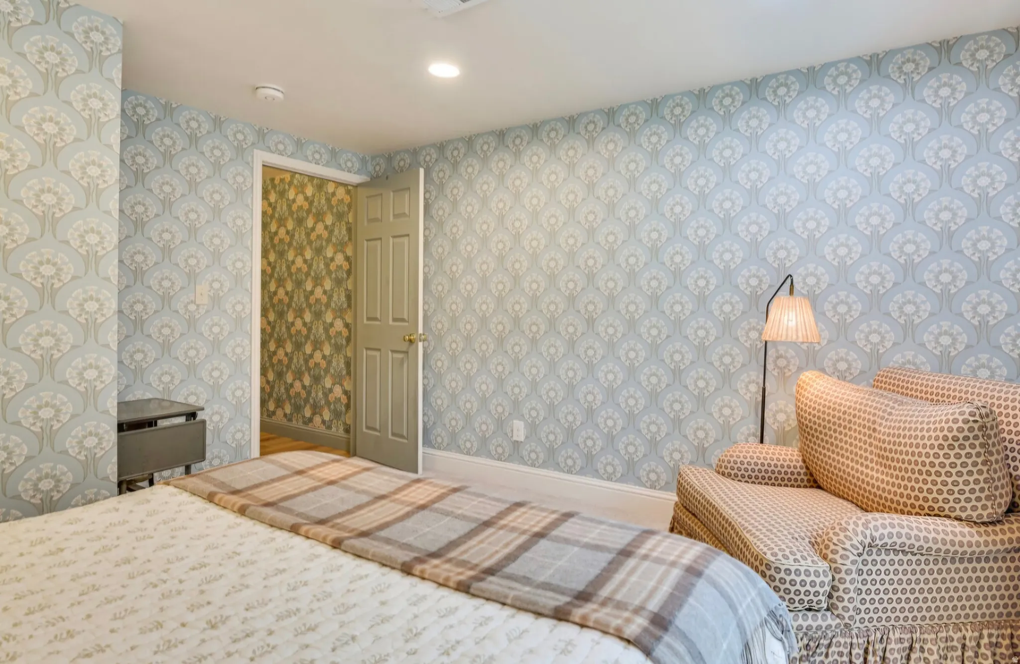 Room featuring patterned wallpaper, a paneled door with hardware, and white baseboards