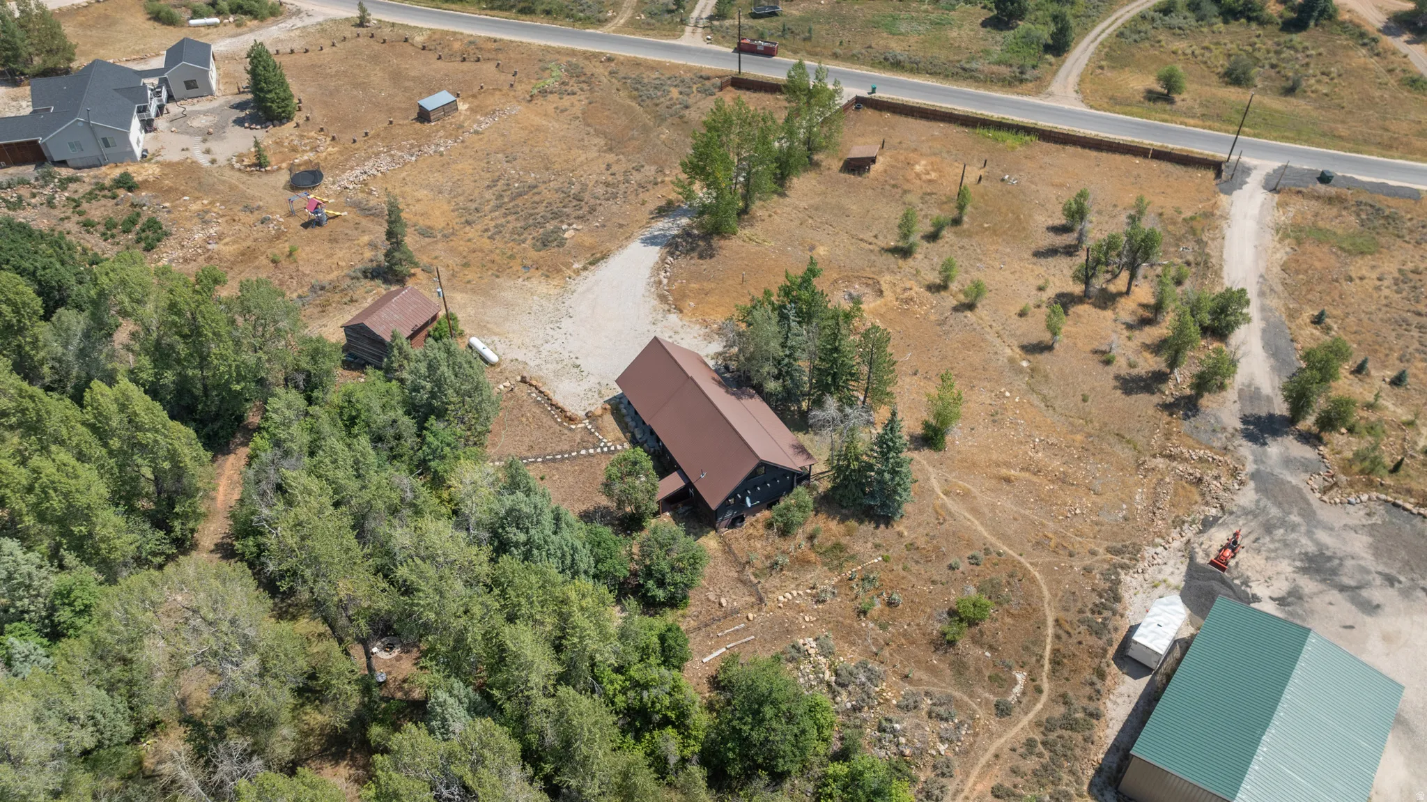 Aerial perspective showcasing a property with extensive natural landscaping and multiple structures