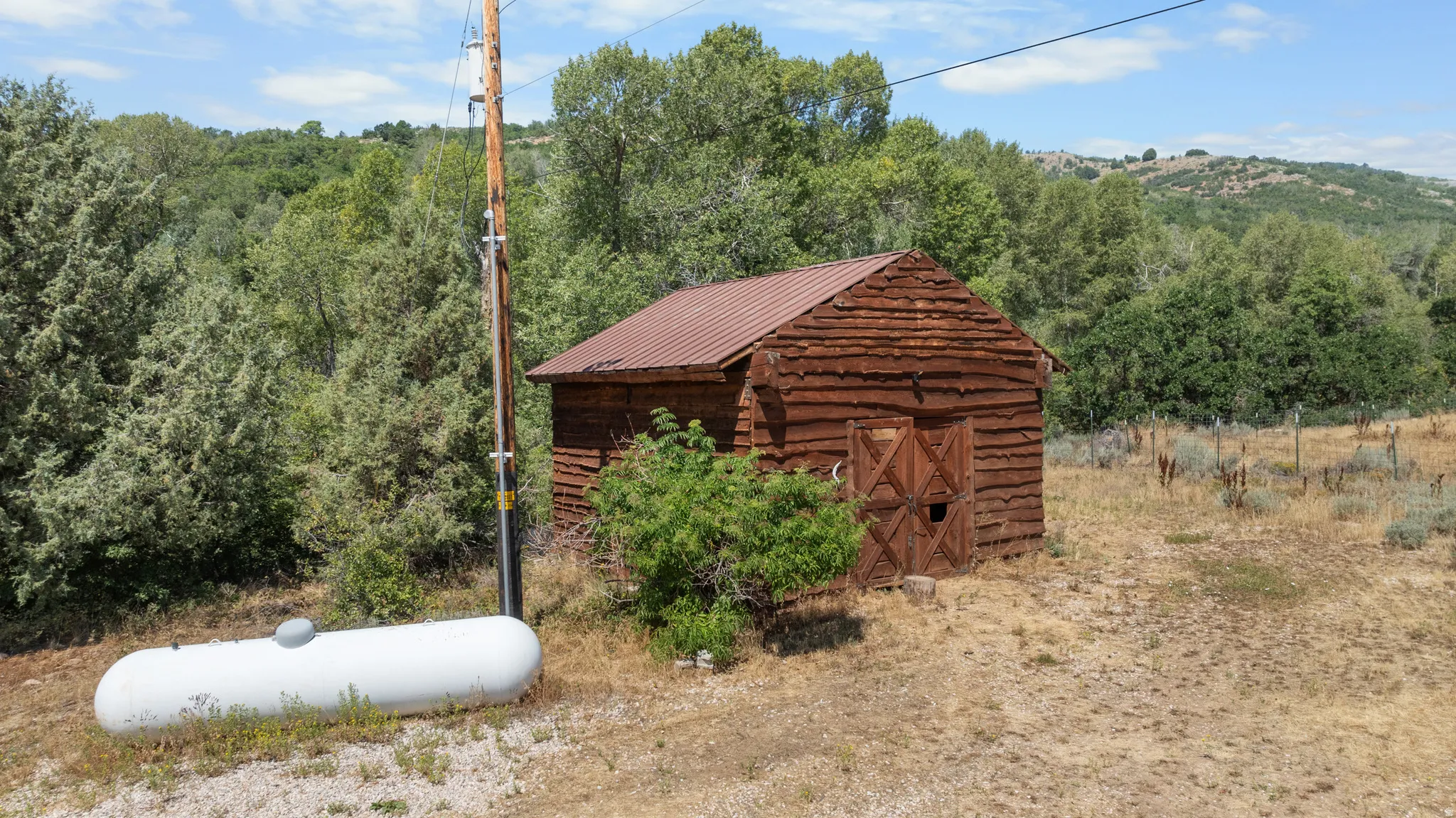 Rustic outbuilding featuring log construction and a metal roof