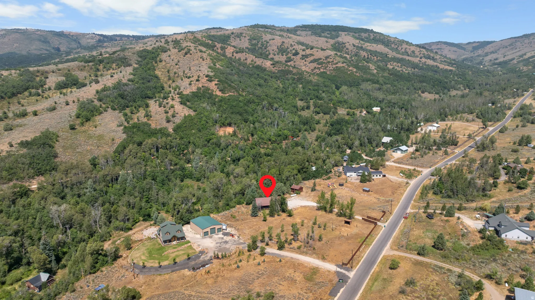 Expansive mountain property featuring a residential structure, detached garage, and direct road access
