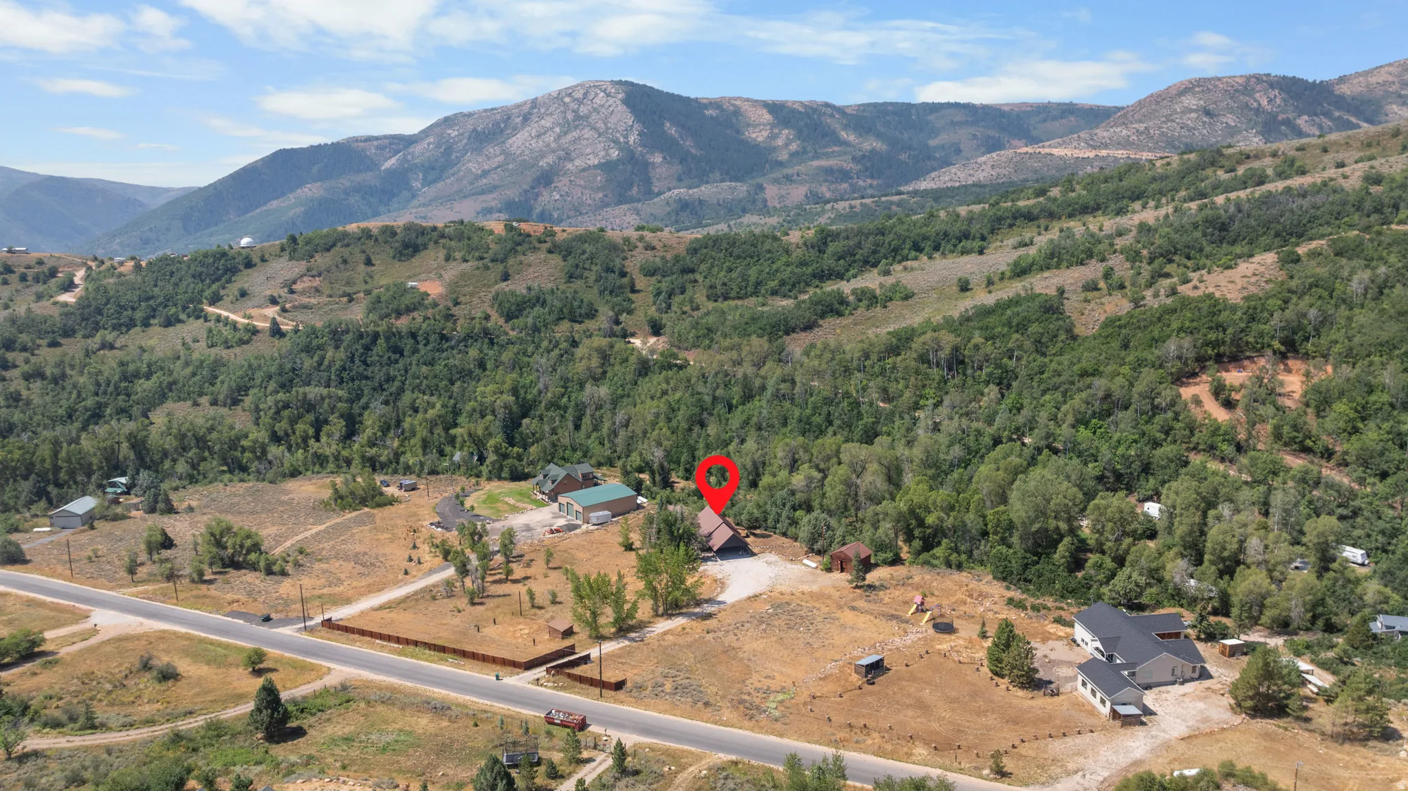 Property situated on a sloped, tree-covered lot with a prominent mountain backdrop