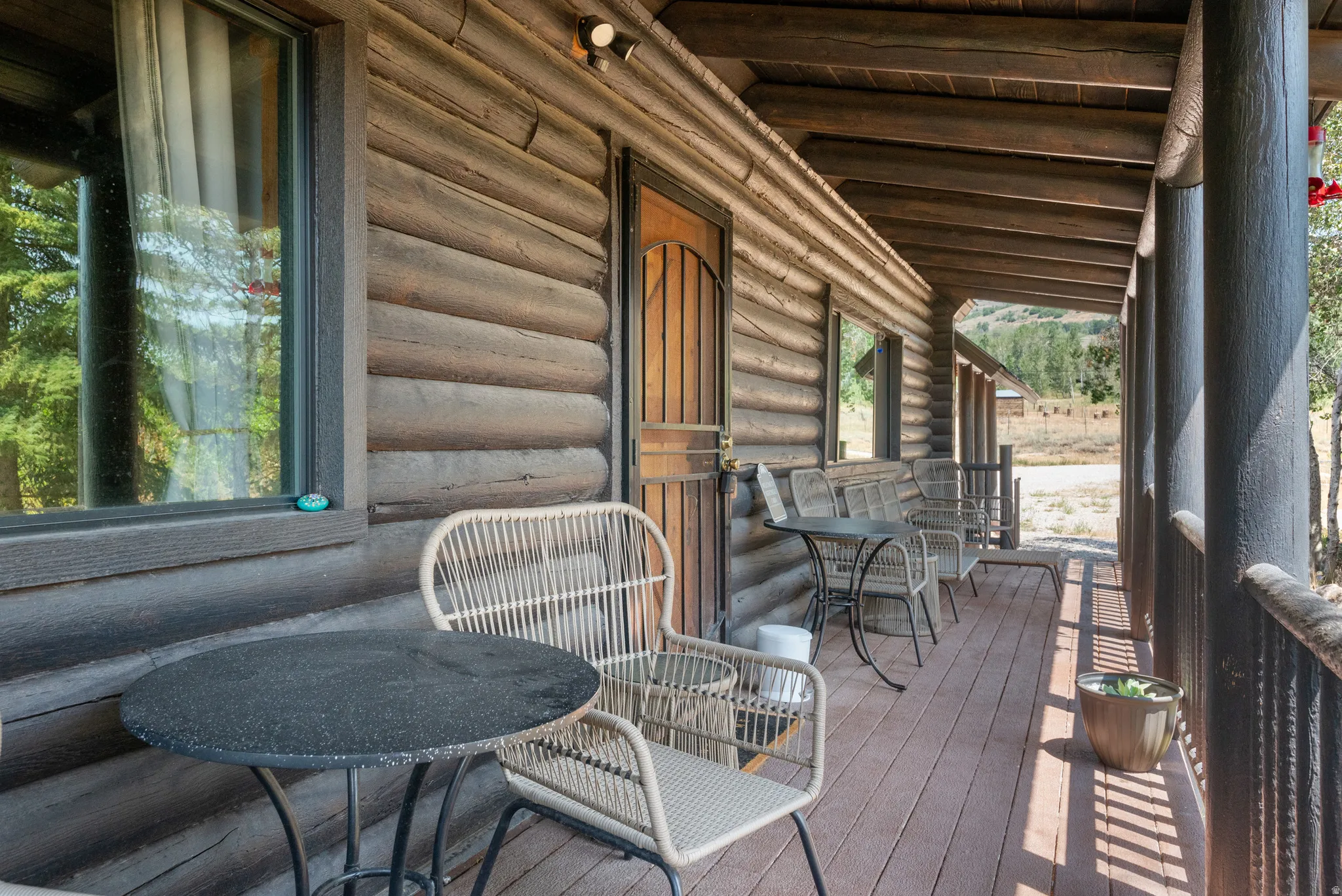 Expansive covered porch featuring wood-finish decking, log-style columns, and a log-cabin exterior