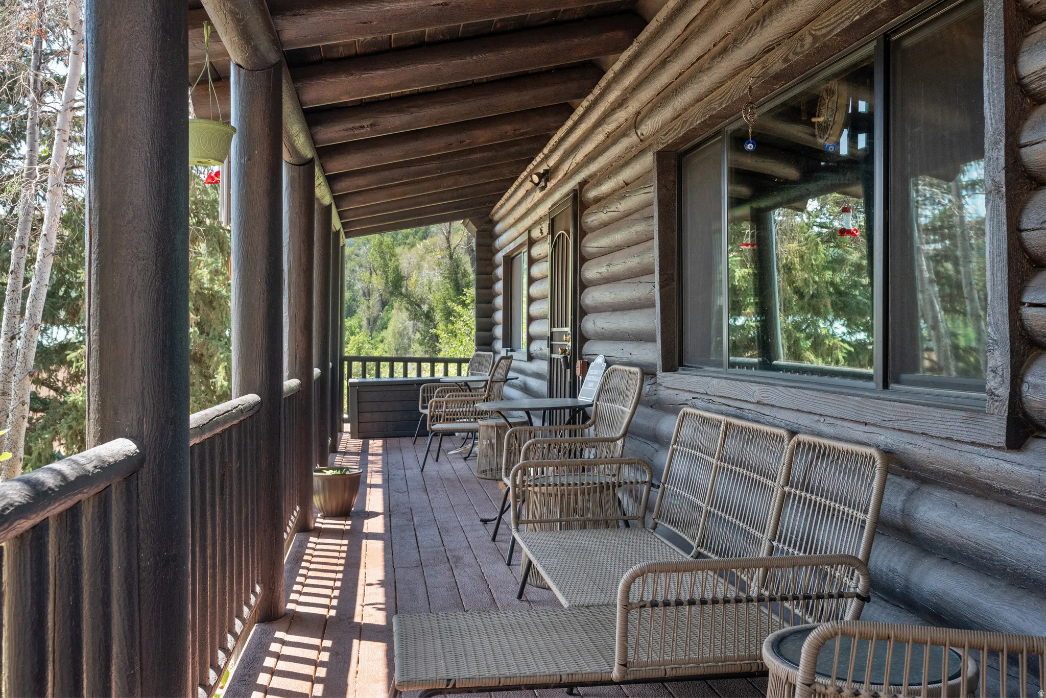 Expansive covered porch featuring a wood-finish deck, robust log construction, and a full-length wooden railing