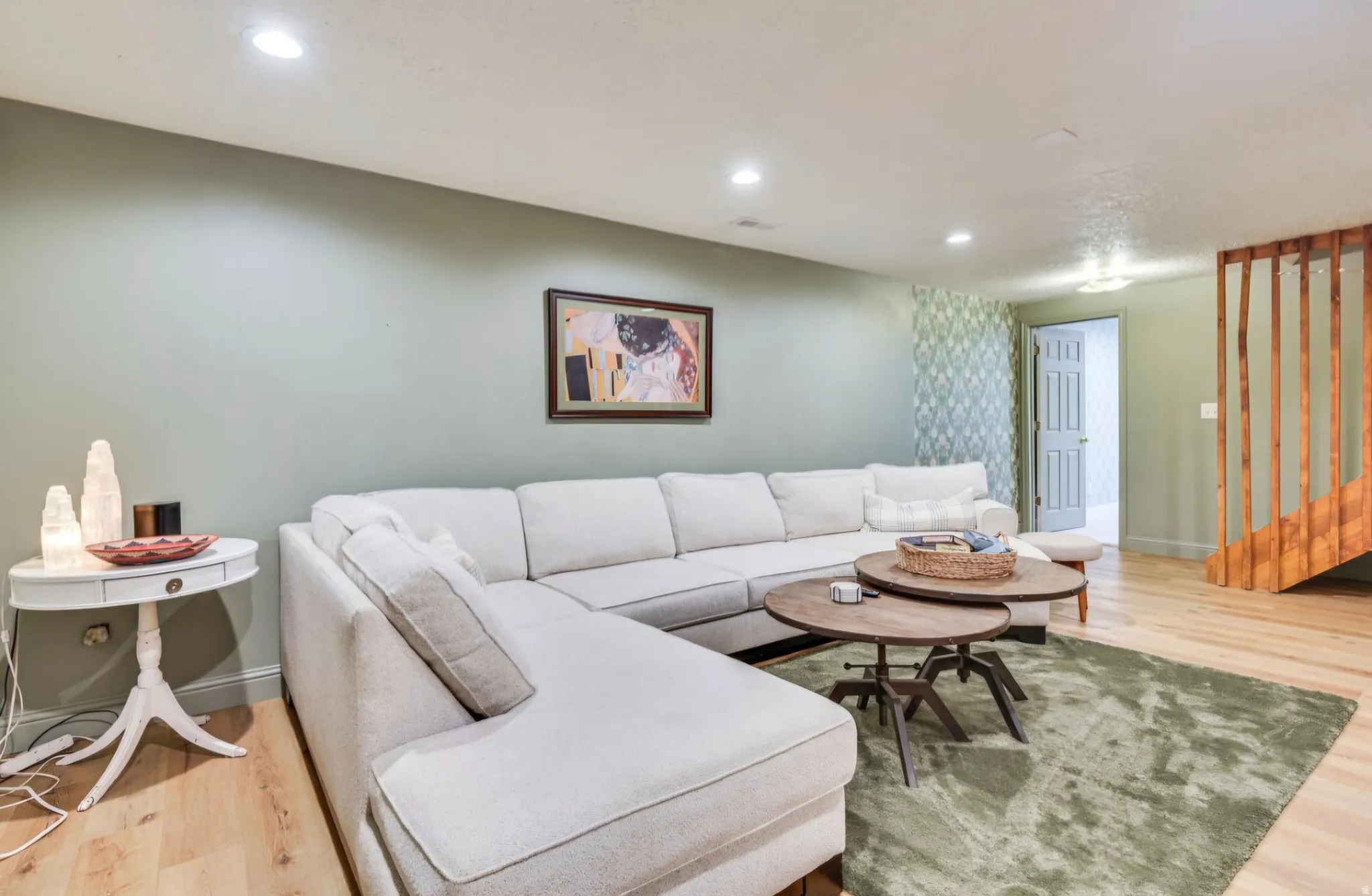 Spacious room featuring light wood-finish flooring, recessed lighting, and a partial decorative wall