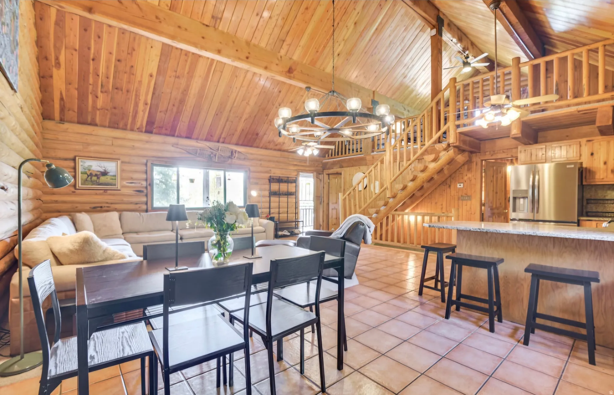 Expansive great room featuring a vaulted wood-plank ceiling, natural log walls, and large windows