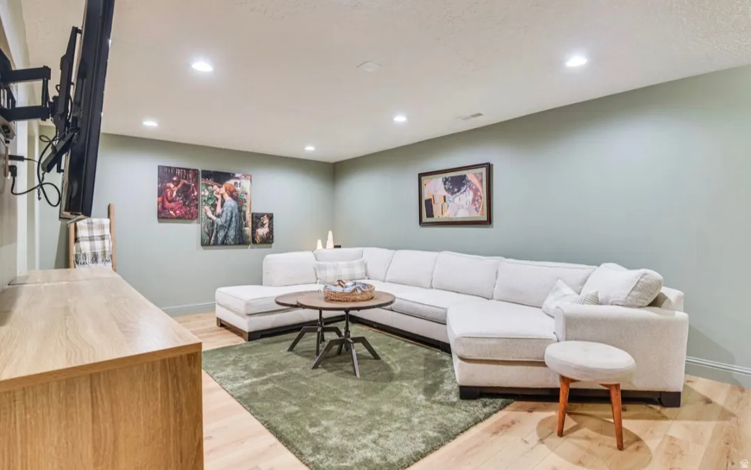 Finished lower level featuring recessed lighting, light wood-finish flooring, and a wall-mounted television bracket
