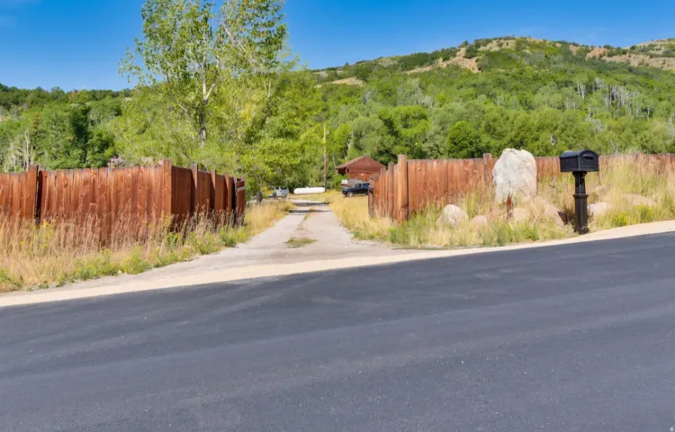 Gravel driveway framed by natural wood fencing and natural landscaping