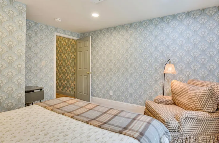 Room featuring patterned wallpaper, a paneled door with hardware, and white baseboards