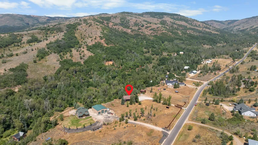 Expansive mountain property featuring a residential structure, detached garage, and direct road access