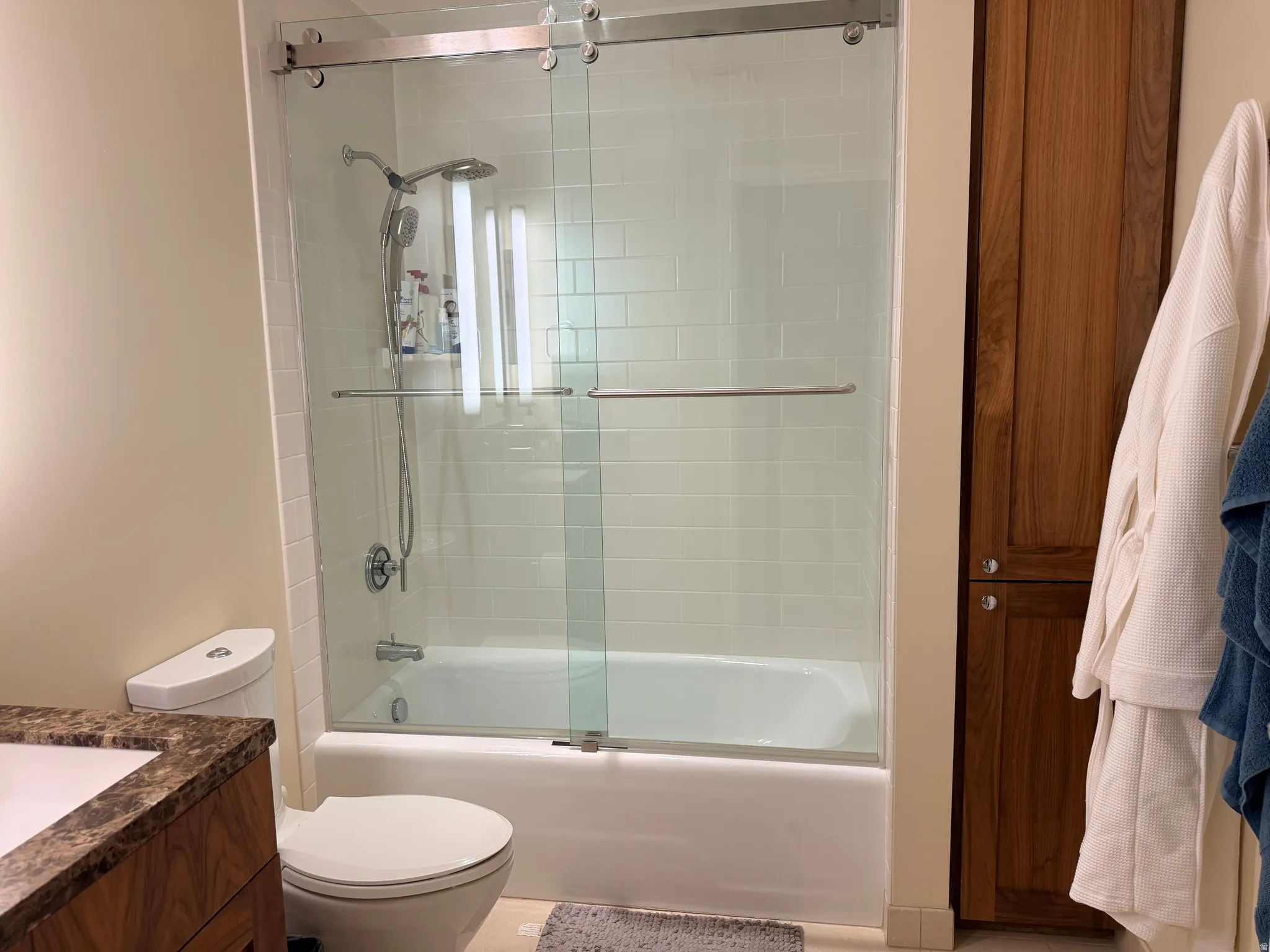 Contemporary bathroom featuring a frameless glass sliding shower enclosure with brushed nickel hardware, white subway tile surround, and an integrated soaking tub