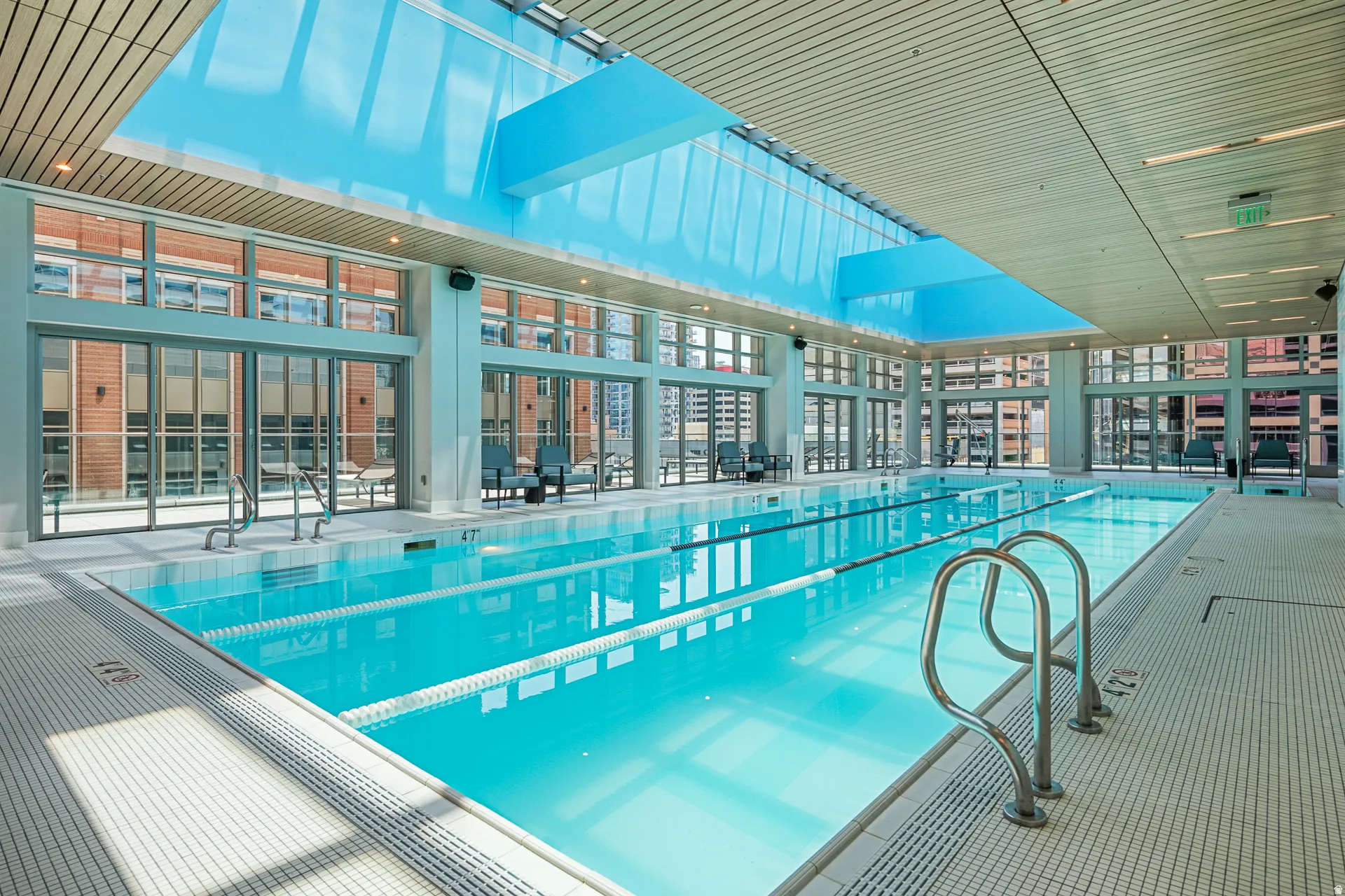 Modern indoor aquatic facility featuring a 25-meter lap pool with clearly marked lane divisions, stainless steel handrails, and non-slip deck surfacing
