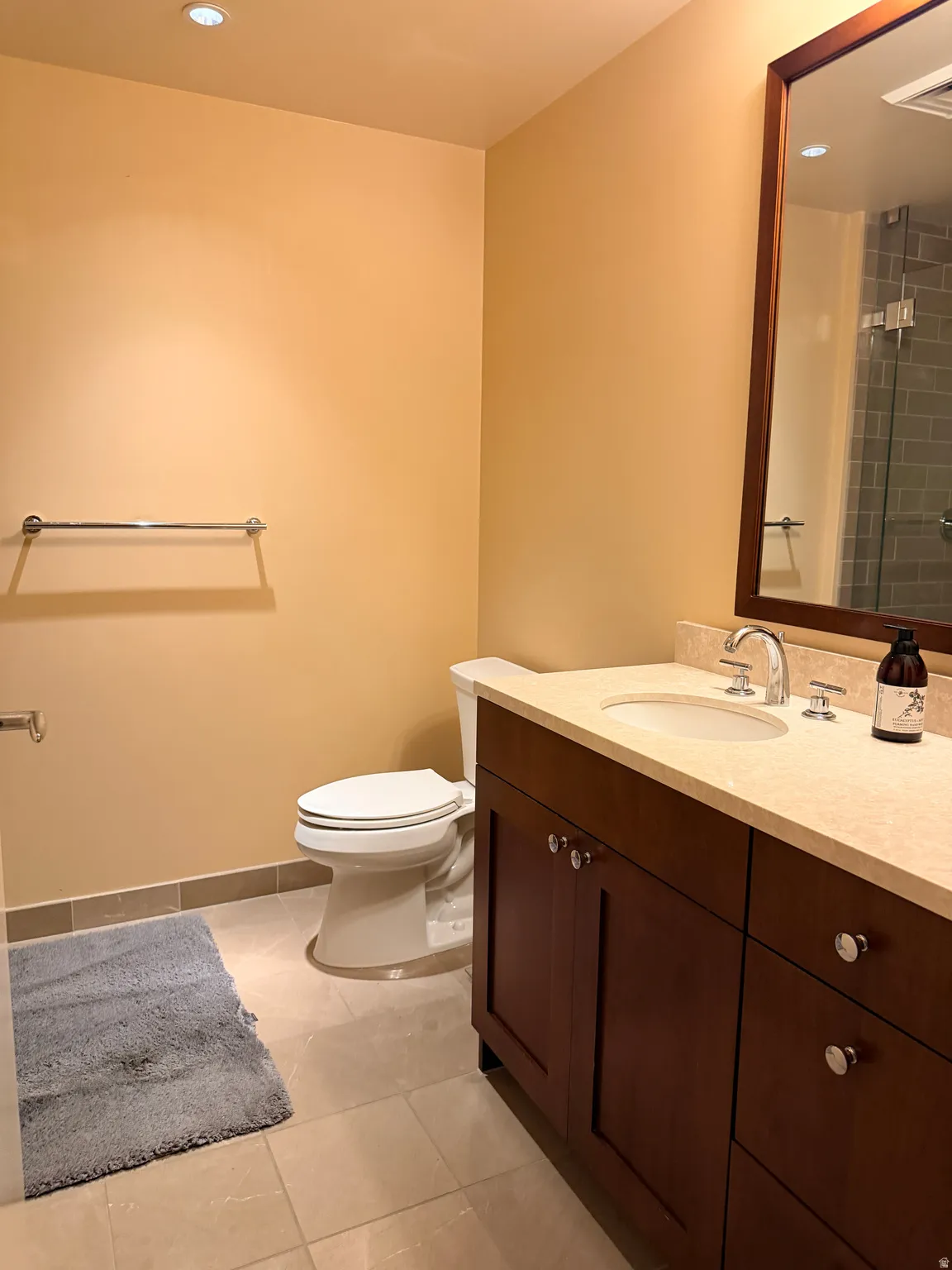 Spa-inspired bathroom featuring a wood-finish vanity with ample storage, white porcelain sink, and polished chrome fixtures