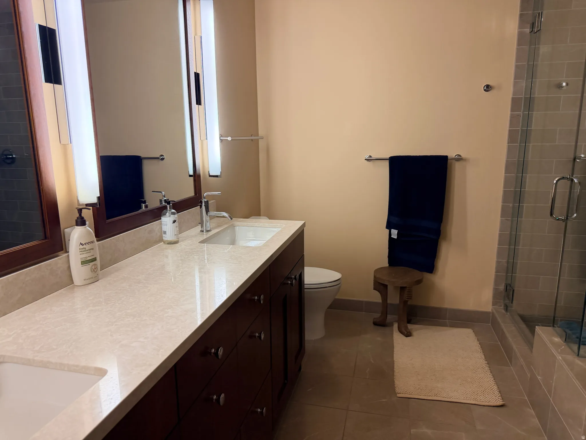 Bathroom vanity with dual undermount sinks, stone-finish countertop, and dark wood cabinetry