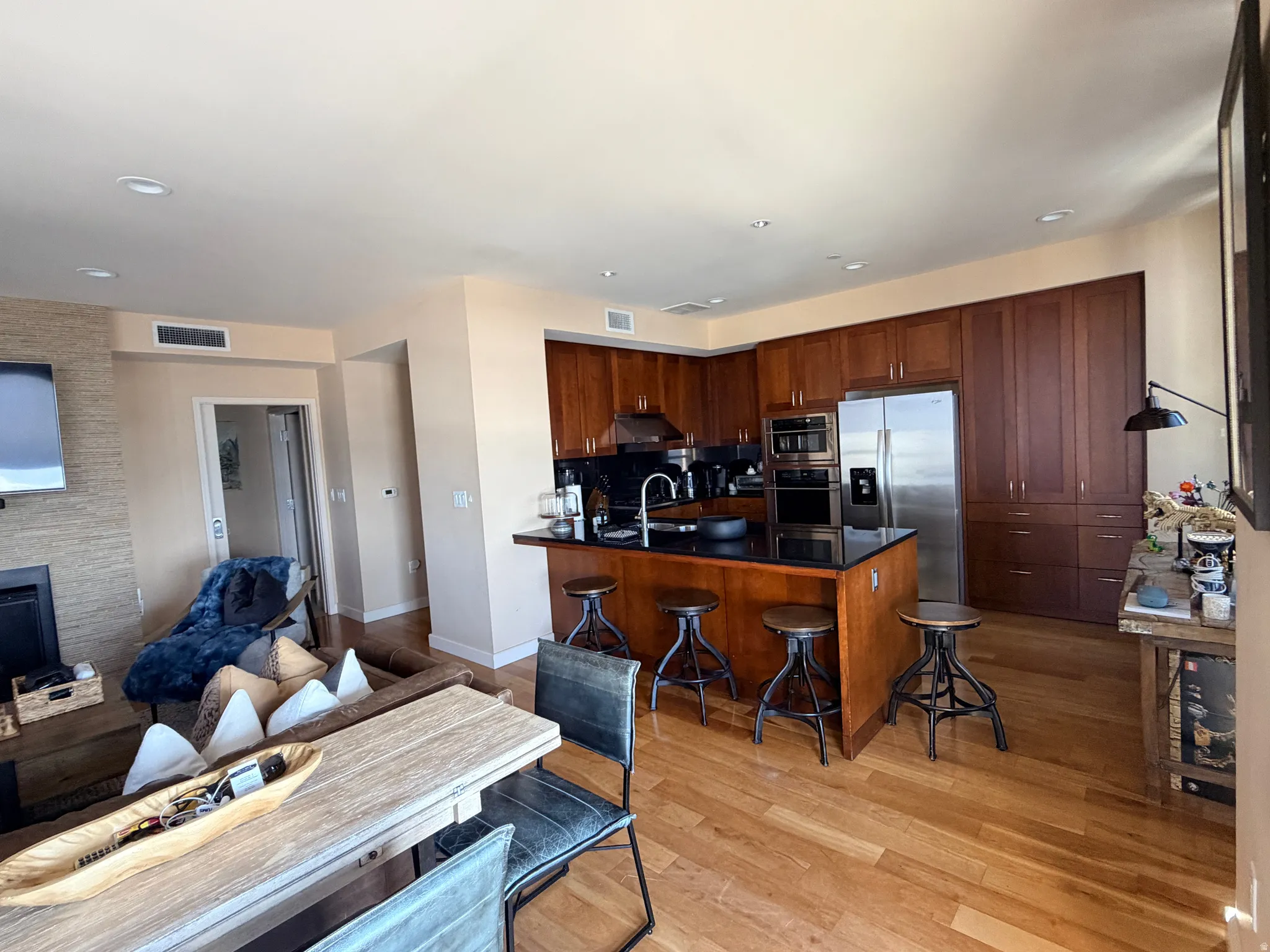 Open-concept living area featuring wood-finish flooring, recessed lighting, and a kitchen with rich wood cabinetry