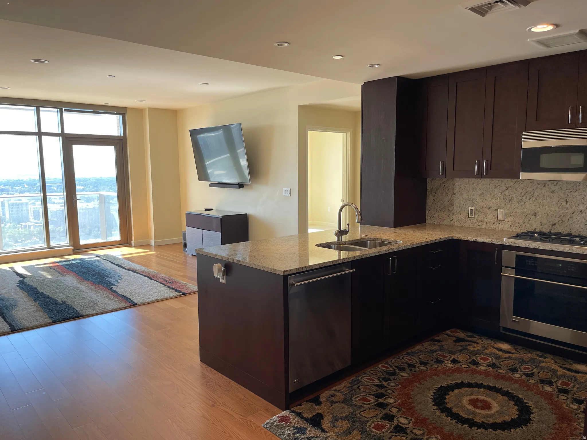 Modern open-concept living featuring a chef's kitchen with dark cabinetry, stainless steel appliances, granite countertops, and a substantial island with seating