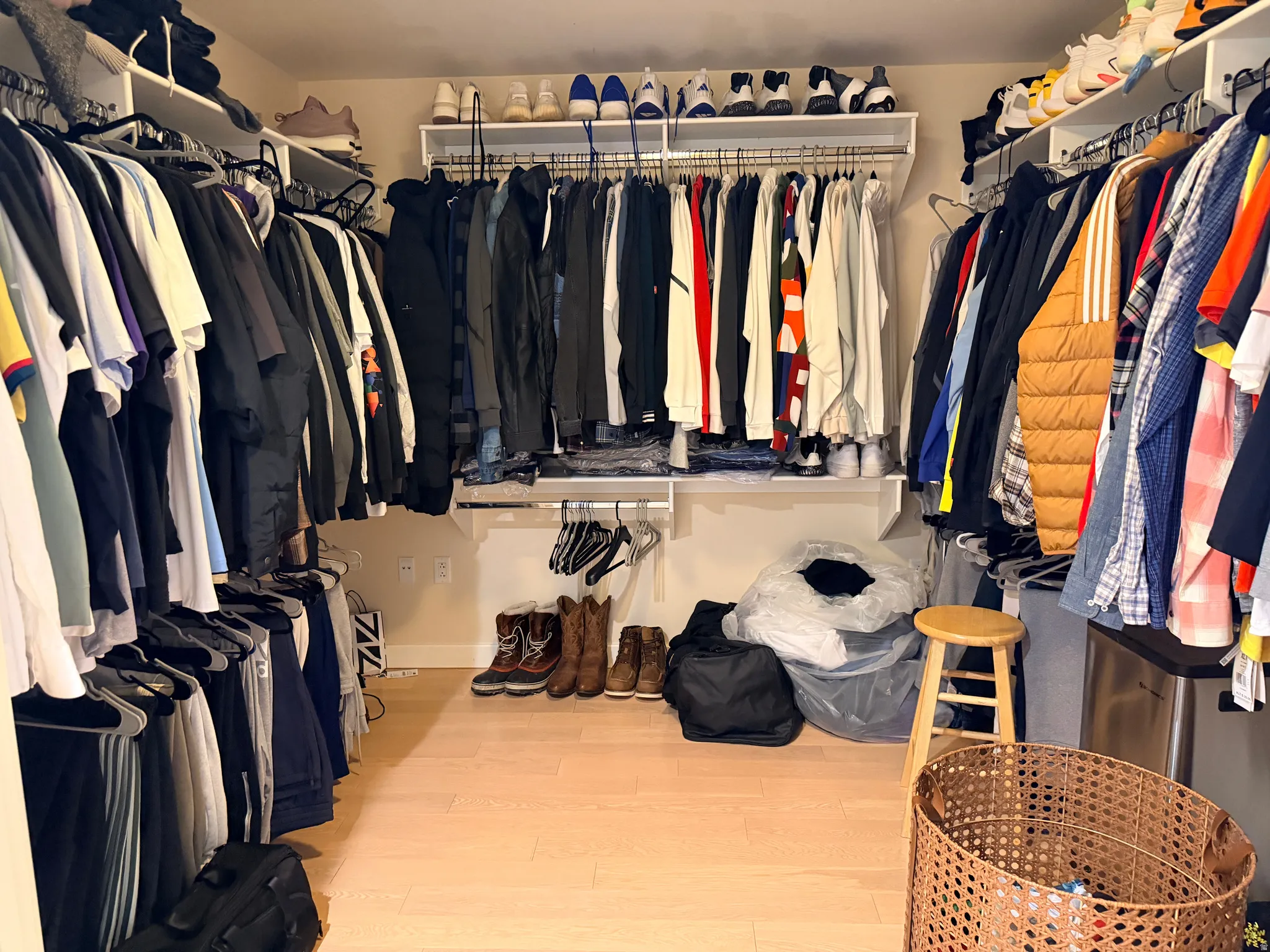 Spacious walk-in closet featuring extensive built-in shelving and rod systems, wood-finish flooring, and ample storage capacity for a comprehensive wardrobe collection