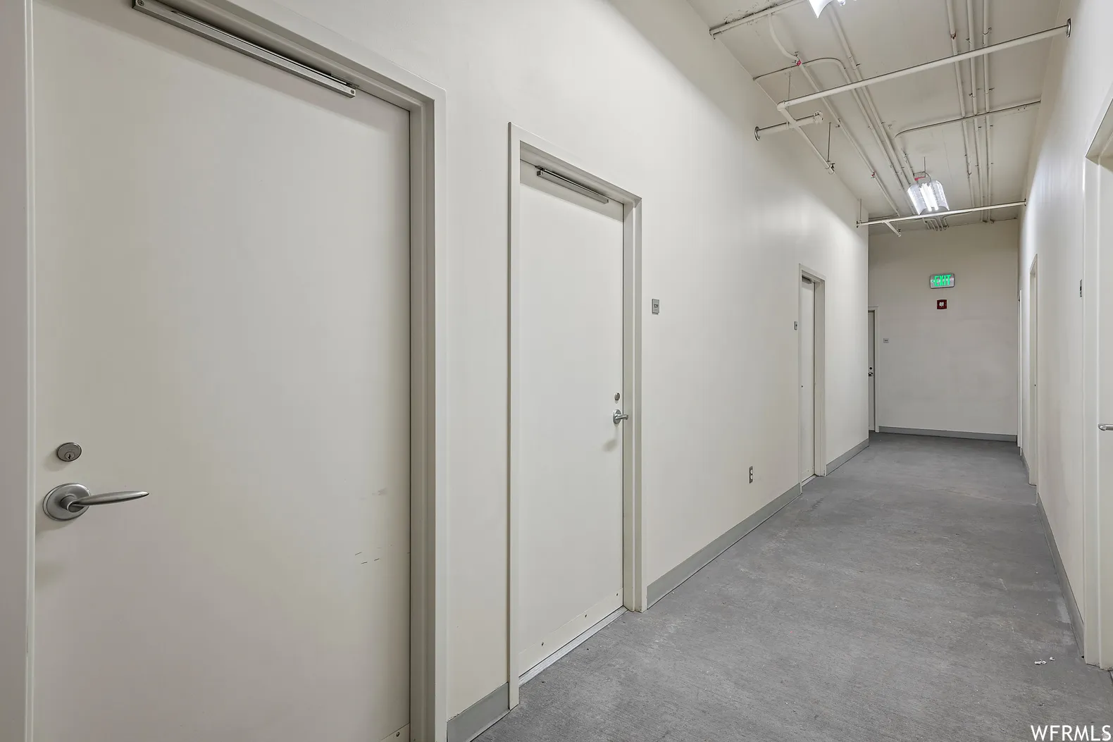 Three storage units come with condo + Three reserved parking spaces  Modern commercial hallway featuring clean white composite doors with brushed metal hardware, polished concrete flooring, and recessed ceiling lighting