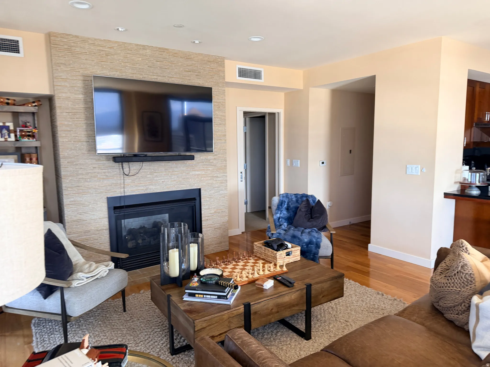 Living area with a stacked stone-finish fireplace surround, recessed lighting, and hardwood flooring