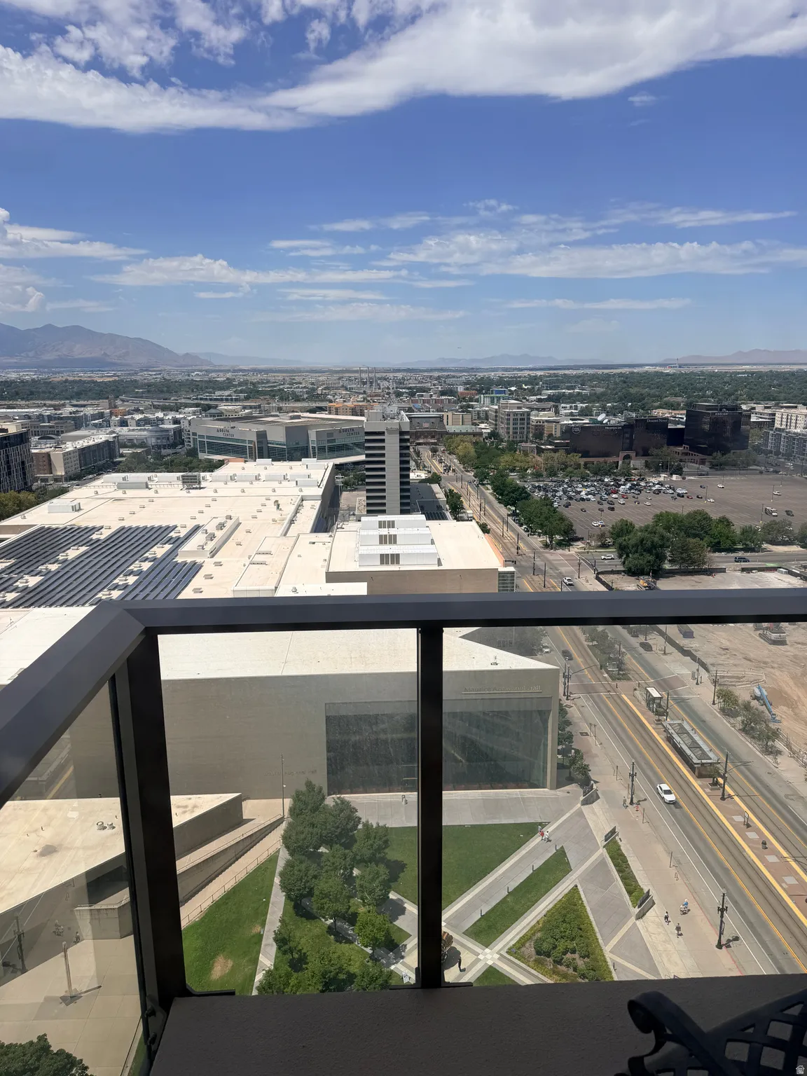 Expansive urban panorama from a high-level balcony with glass and dark metal railings