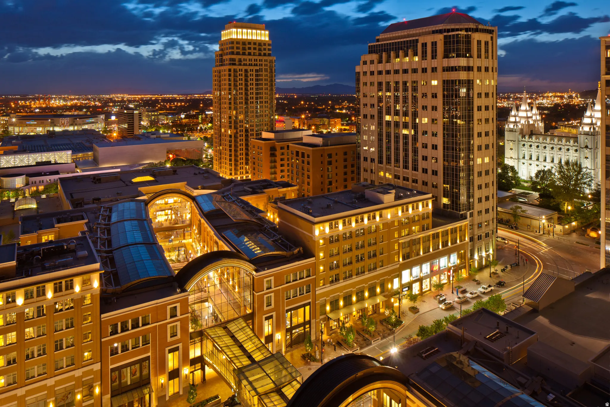 Urban skyline setting featuring illuminated mid-rise and high-rise residential towers with warm architectural lighting