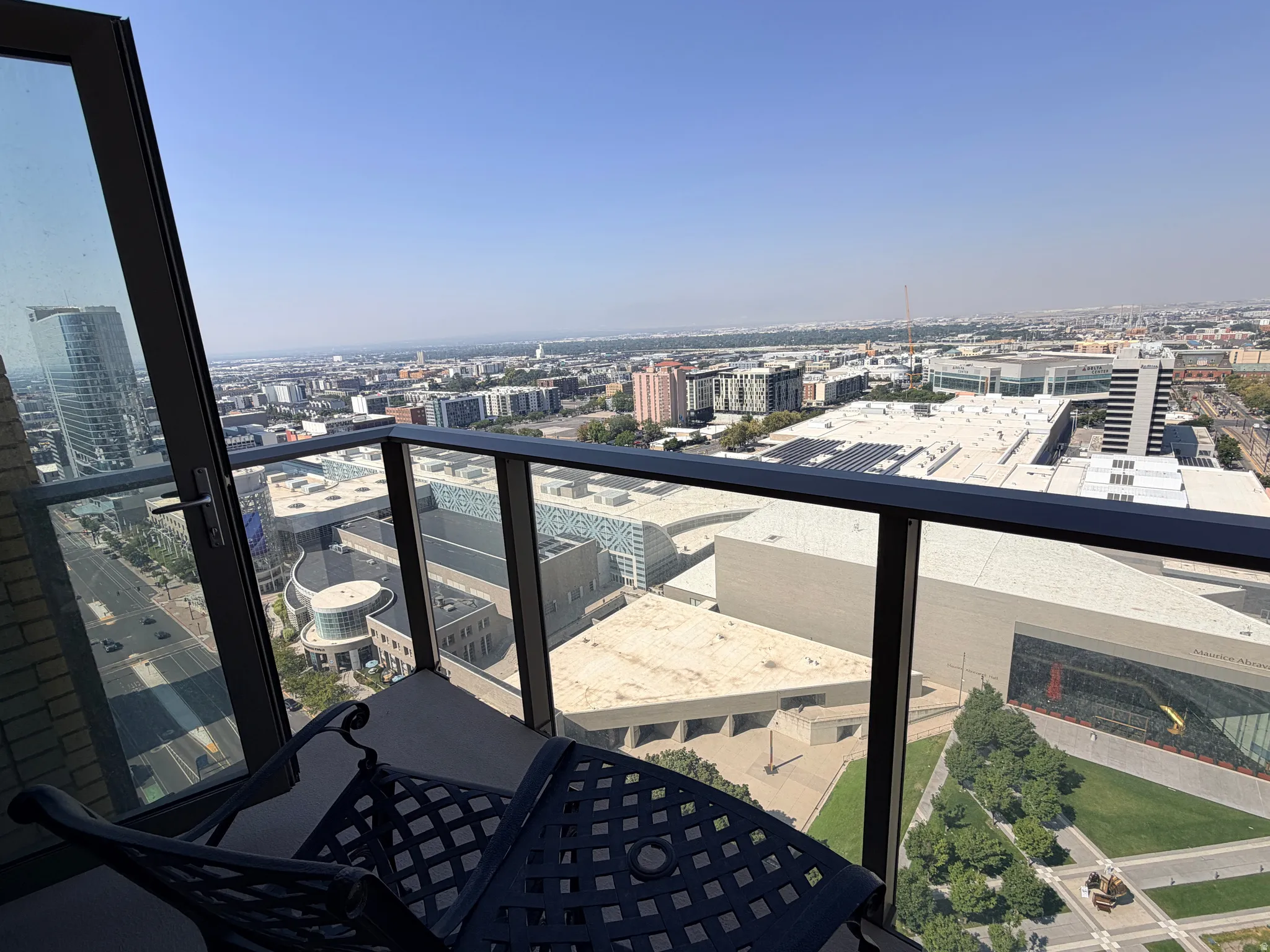 Private balcony featuring a glass and metal railing, offering expansive urban and distant mountain vistas