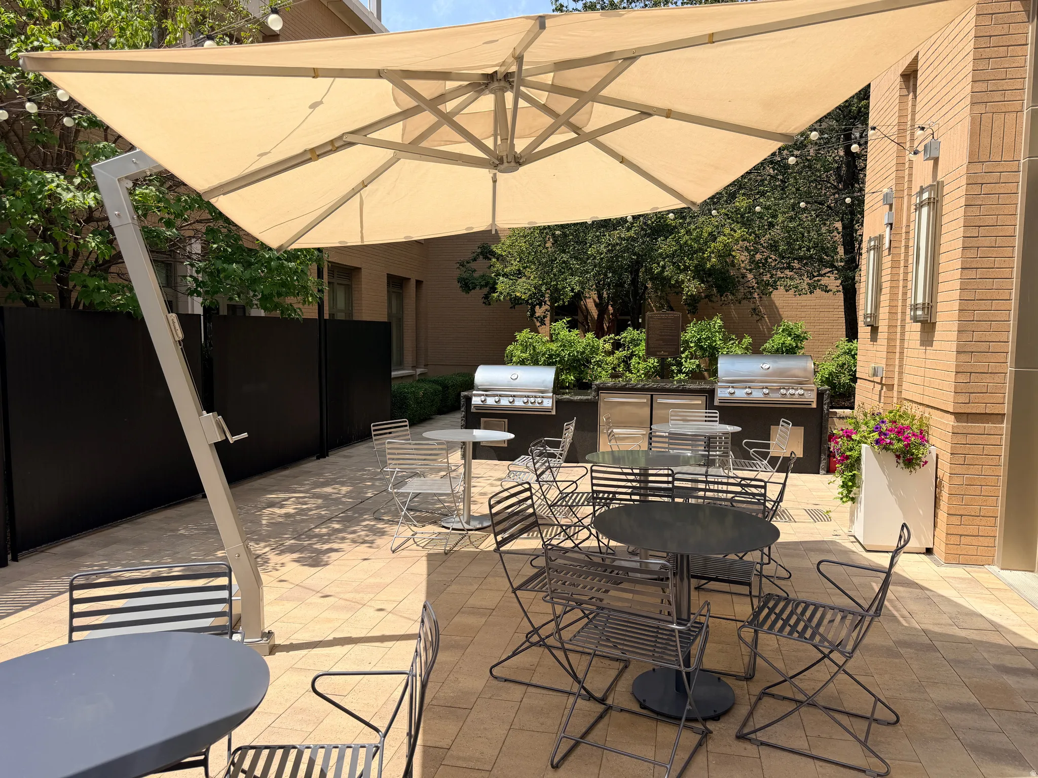 Outdoor patio space featuring a large cantilever umbrella, paver flooring, and an outdoor kitchen area with two built-in grills
