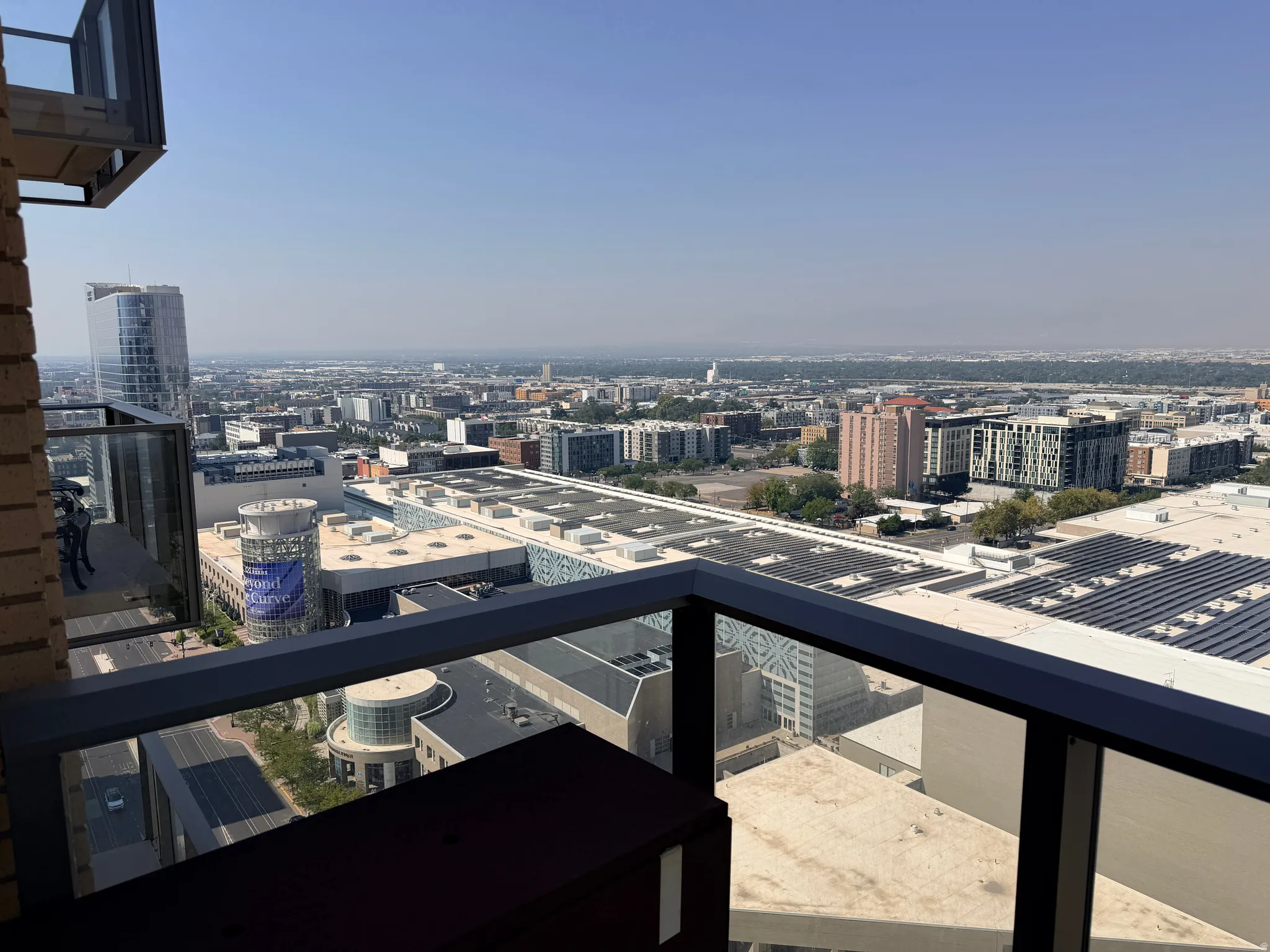 Expansive city skyline and distant landscape views from a glass-paneled balcony