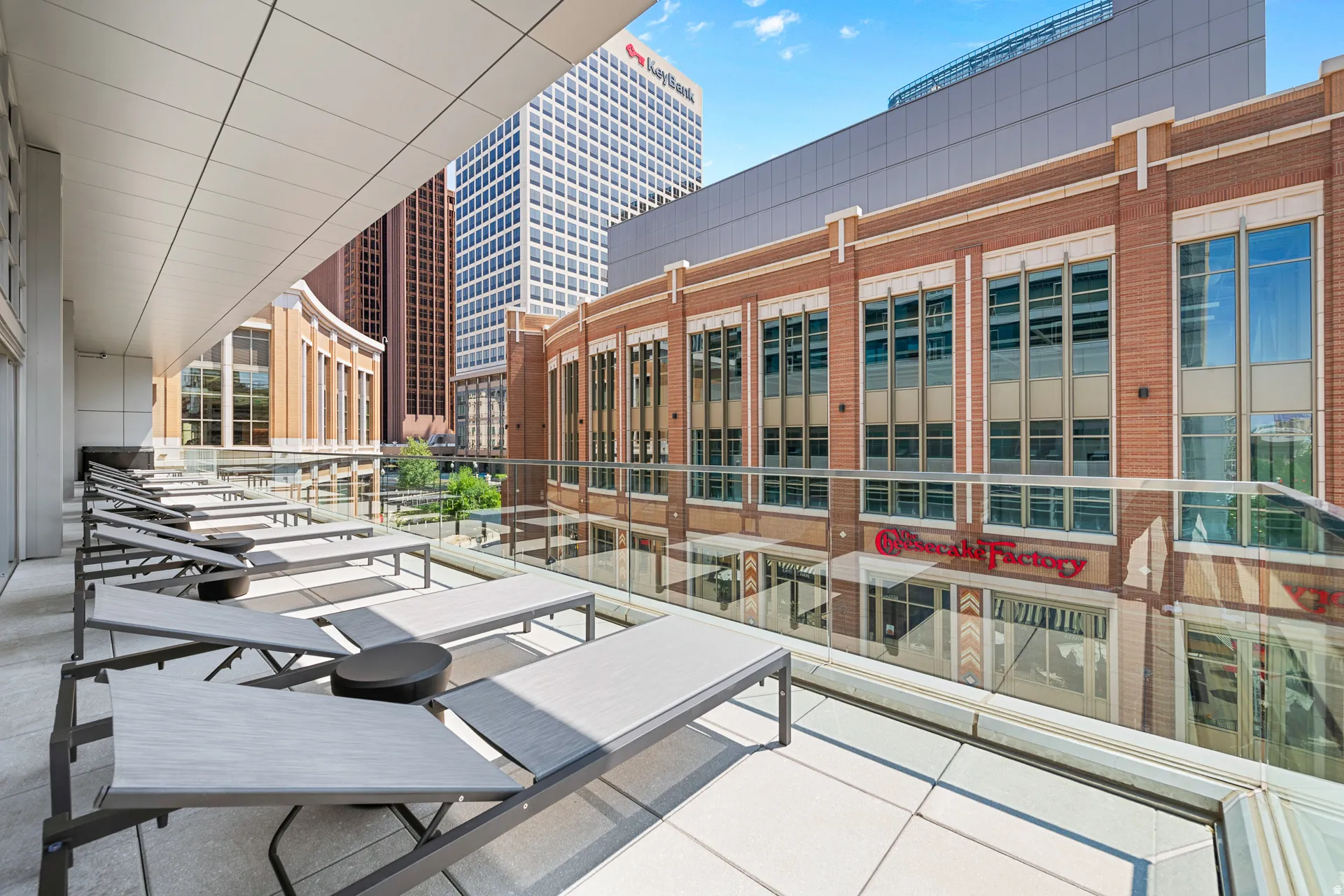 Rooftop terrace featuring multiple lounge chairs, polished concrete flooring, glass railings with metal framing, and abundant natural light