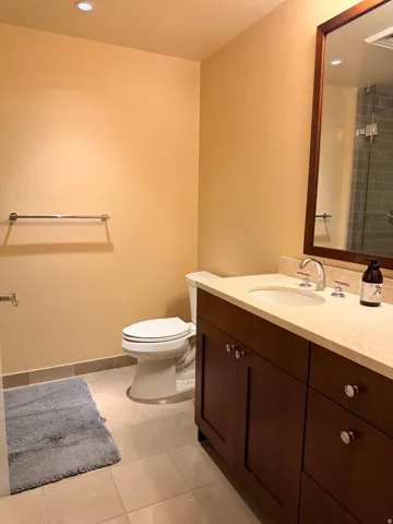 Spa-inspired bathroom featuring a wood-finish vanity with ample storage, white porcelain sink, and polished chrome fixtures