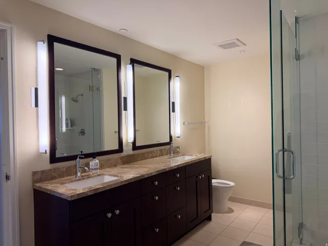 Bathroom featuring a dual vanity with a light brown countertop and dark wood cabinetry