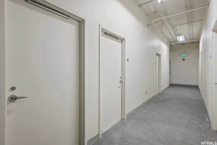 Three storage units come with condo + Three reserved parking spaces  Modern commercial hallway featuring clean white composite doors with brushed metal hardware, polished concrete flooring, and recessed ceiling lighting