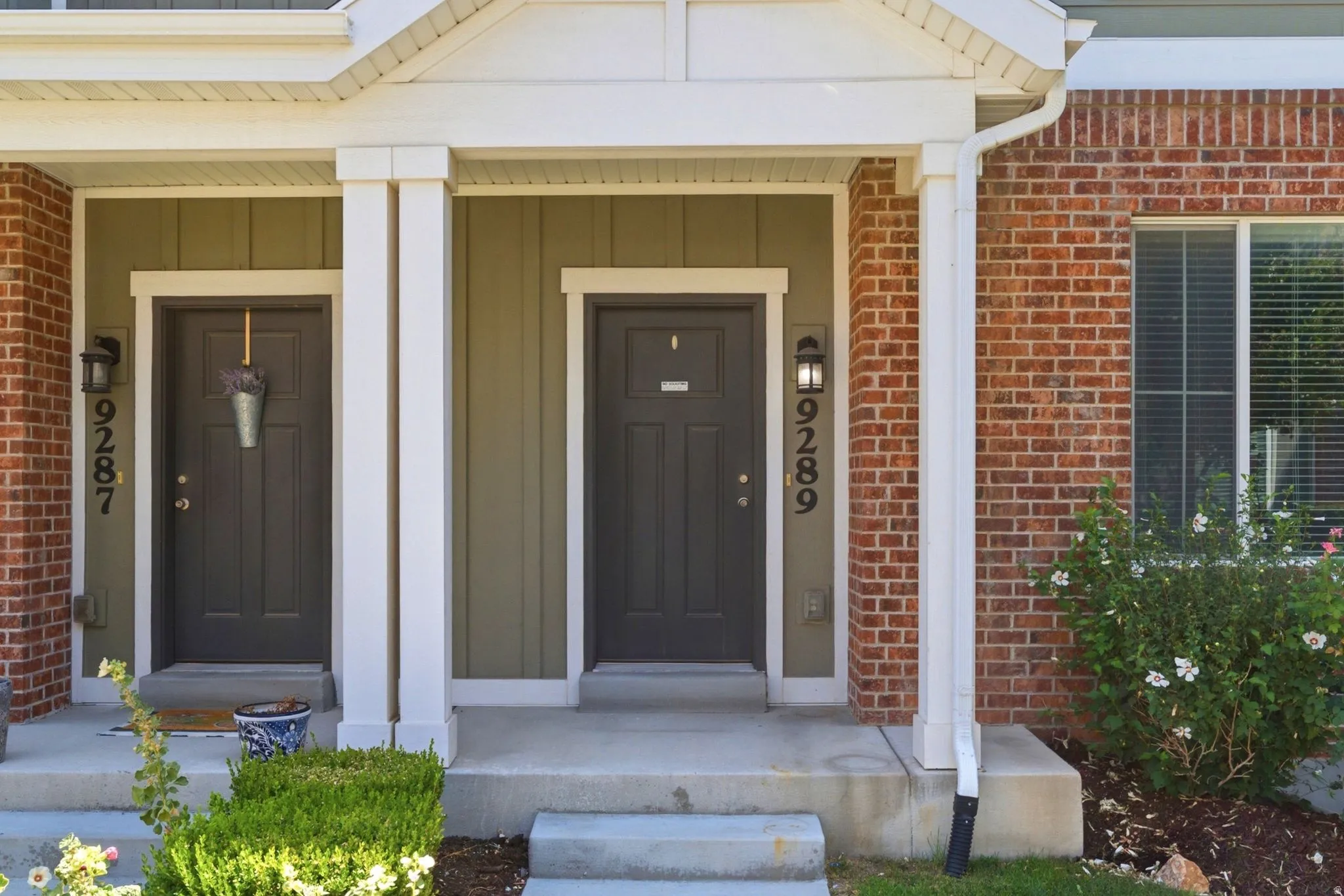 Brick and siding exterior featuring white trim and a covered entryway