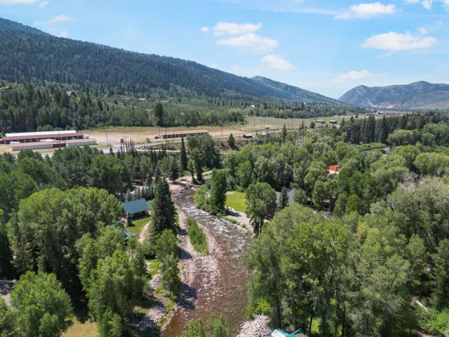 Riverfront property featuring a forested landscape and mountainous backdrop