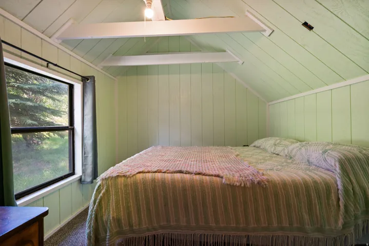 Room featuring pitched plank ceiling, exposed white beams, and light green vertical plank walls