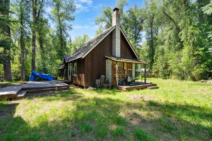 Rustic exterior featuring wood siding, a prominent brick chimney, and a covered front porch